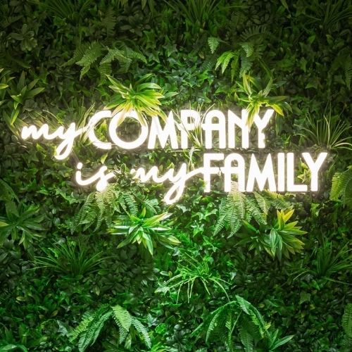 litery ozdobne My company is my family na zielonej ściance