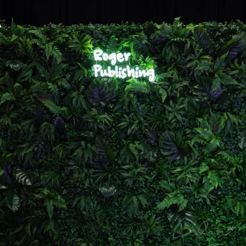 Neon świetlny na zielonej ściance na event marki Roger Publishing